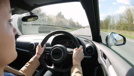 Young-woman-driving-in-a-car,-over-shoulder-view