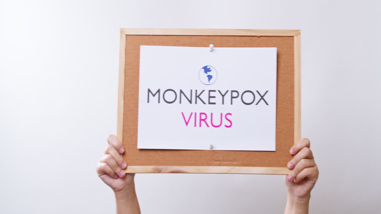 Woman hand shows a sheet of paper with the inscription monkeypox virus