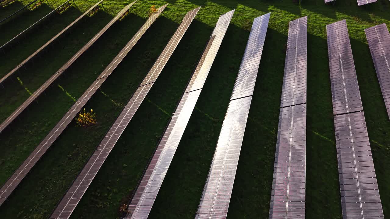 Solar panels capture sunlight in a green field from an aerial view
