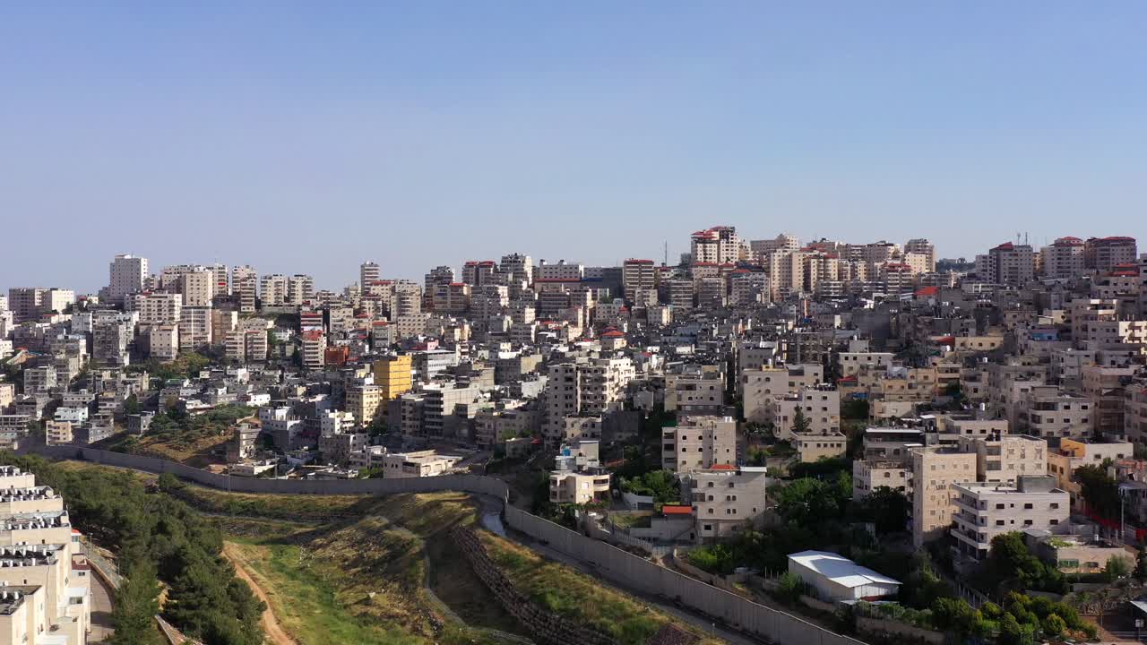 Panoramic view of a densely populated city with a prominent separation wall