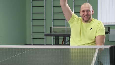 a man in a wheelchair plays ping pong. people with disabilities play table tennis. rehabilitation of the disabled. paralympic sport.