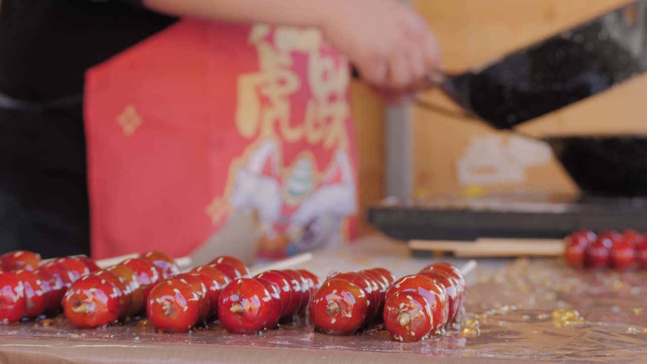 Making fruits in boiling caramel close-up. Chinese winter sweet dessert Tanghulu street food.Berries, grapes, tangerine and others fruit caramelized in sugar. Asian street market with traditional food.. High quality 4k footage