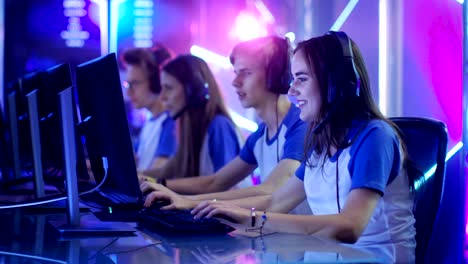 team of teenage gamers get ready for esport tournament, put on their headsets. tournament area/ internet cafe looks cool with neon lights.