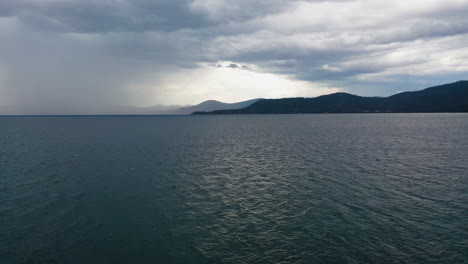 Aerial-tracking-shot-over-water-surface-of-lake-Tahoe,-gloomy-and-rainy-day-in-USA