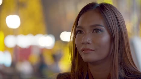 Attractive-young-woman-in-the-city-at-night-smiles-at-the-camera---cinematic-background-bokeh-light