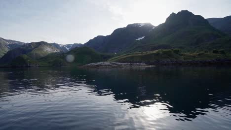 bright sky over summit with reflection on pristine ocean in norway