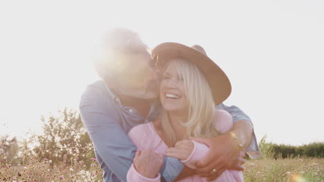 portrait of loving mature couple smiling into camera against flaring sun