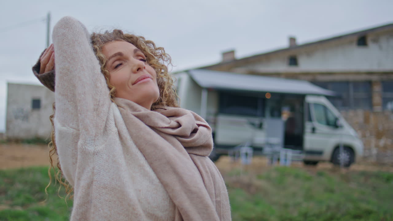 트레일러 캠프 근처의 구름이 가득한 자연에서 휴식을 취하는 조용한 여성 관광객.