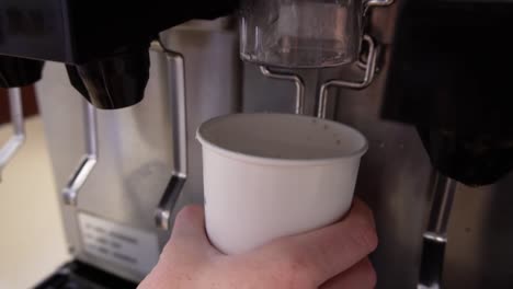 ice dispenser filling a white paper cup, in slow motion