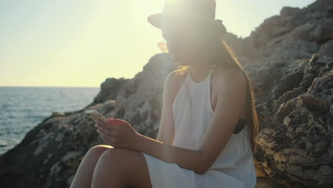 mujer usando el teléfono en un acantilado de la playa