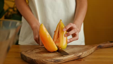 cocinero de cultivos cortando pimienta amarilla en una tabla de madera