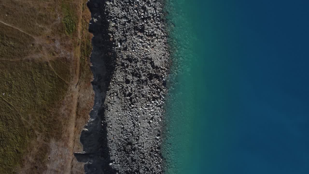 Aerial top down view of clear blue Lake Pukaki on a sunny summer day in New Zealand.
