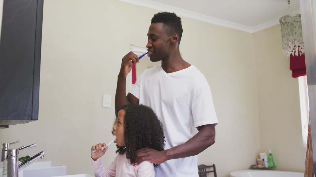 African american father and daughter brushing their teeth
