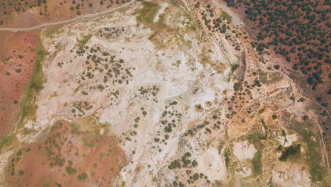 lifeless dry landscape with some bushes growing on. road with few cars parked. aerial view of travertine, california, usa.