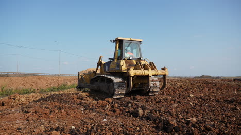 yellow bulldozer on a dirt construction site under a clear sky