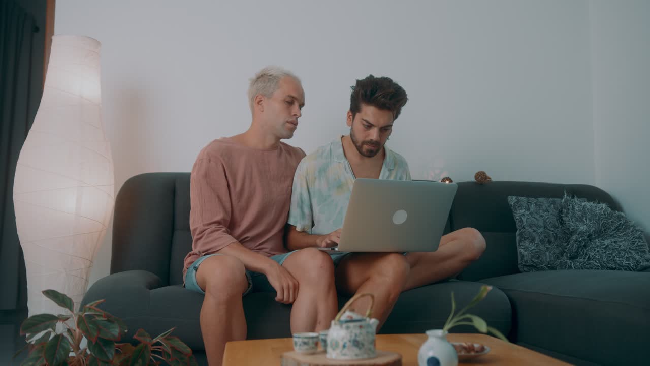 Two men using a laptop at home