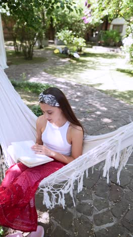 girl reading a book in a hammock in the garden