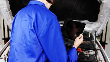 Female-mechanic-using-digital-tablet-while-checking-a-car