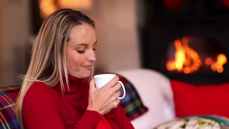 pretty blonde enjoying a hot drink on the couch