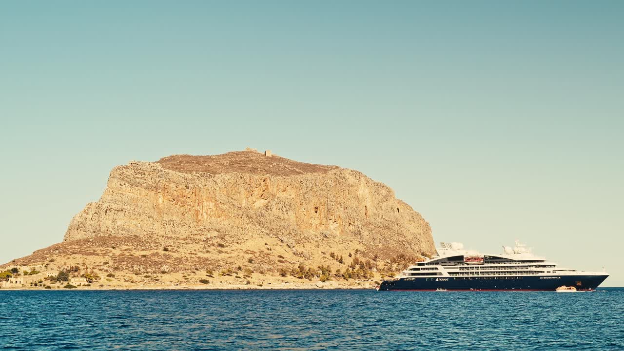 Cruise Ship Docked Near a Mountainous Island