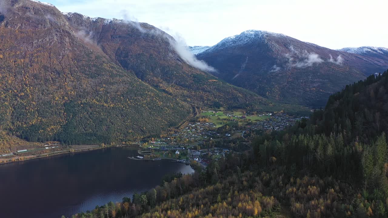 vuelo aéreo sobre la ladera para revelar la ciudad de kinsarvik en un entorno épico en ullensvang noruega - antena con efecto de paralaje durante la soleada mañana de otoño