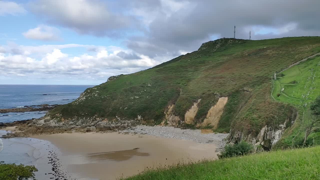 Coastal view of Bretones Beach in Asturias with rocky shore and green hillside