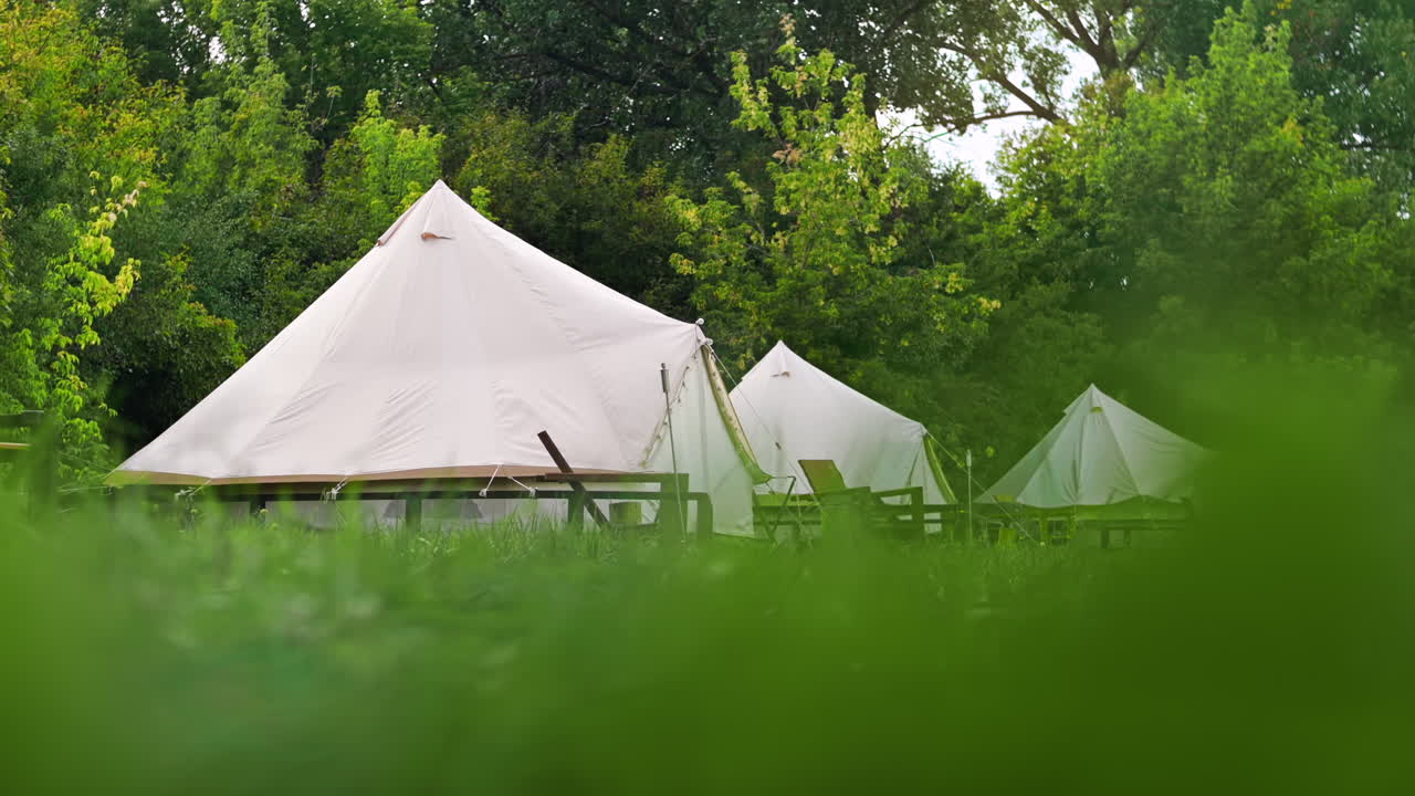 Telte med træstole ved glamping, frodig skov omkring