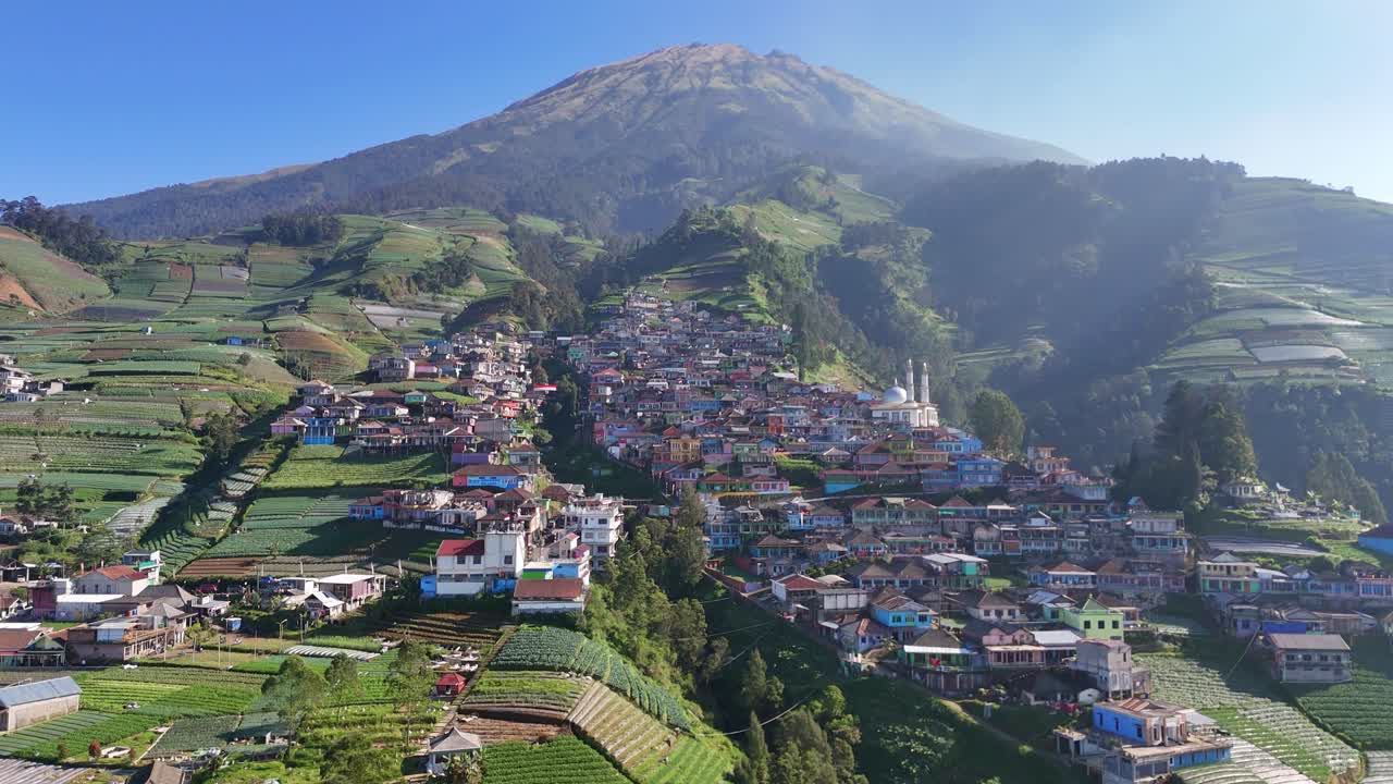 Paesaggio aereo di un tranquillo villaggio di montagna circondato da pendii montani coltivati in una mattina leggermente nebbiosa. Nepal Van Java, Indonesia.