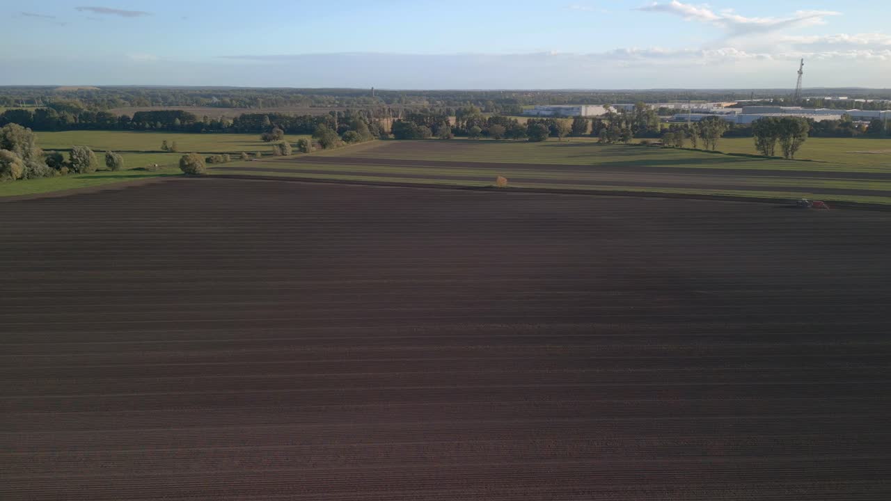 Spektakuläre Drohnen-Luftaufnahme: Kamerafahrt nach rechts über einen Traktor auf einem Herbstfeld in Brandenburg Havelland, Deutschland, Sommer 2022.