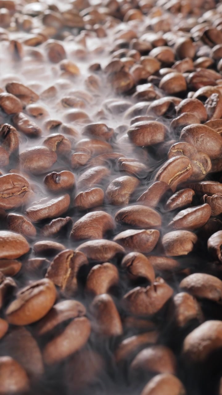 Steaming roasted coffee beans background with selective focus.