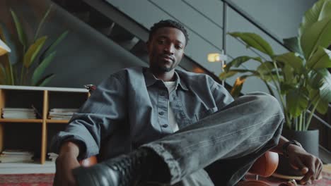 portrait of confident black man sitting with crossed legs in office