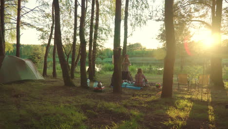 young travelers enjoy holiday on camping trip sitting in evening near tents