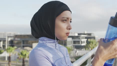 Side-view-of-woman-wearing-hijab-drinking-outside-