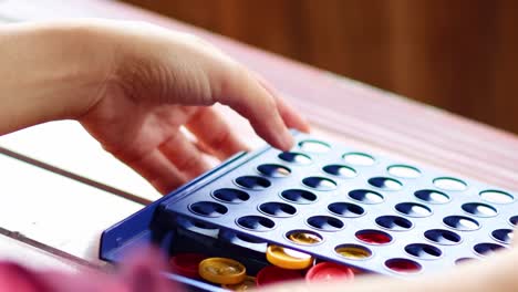 close-up of hands resetting a connect four board, showing red and yellow discs being removed.