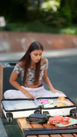 teenager packing suitcase in a park