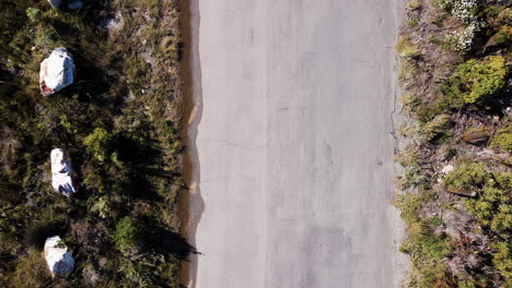 Top-down-aerial-of-cyclist-with-90-degree-shadow-passing-through-top-to-bottom