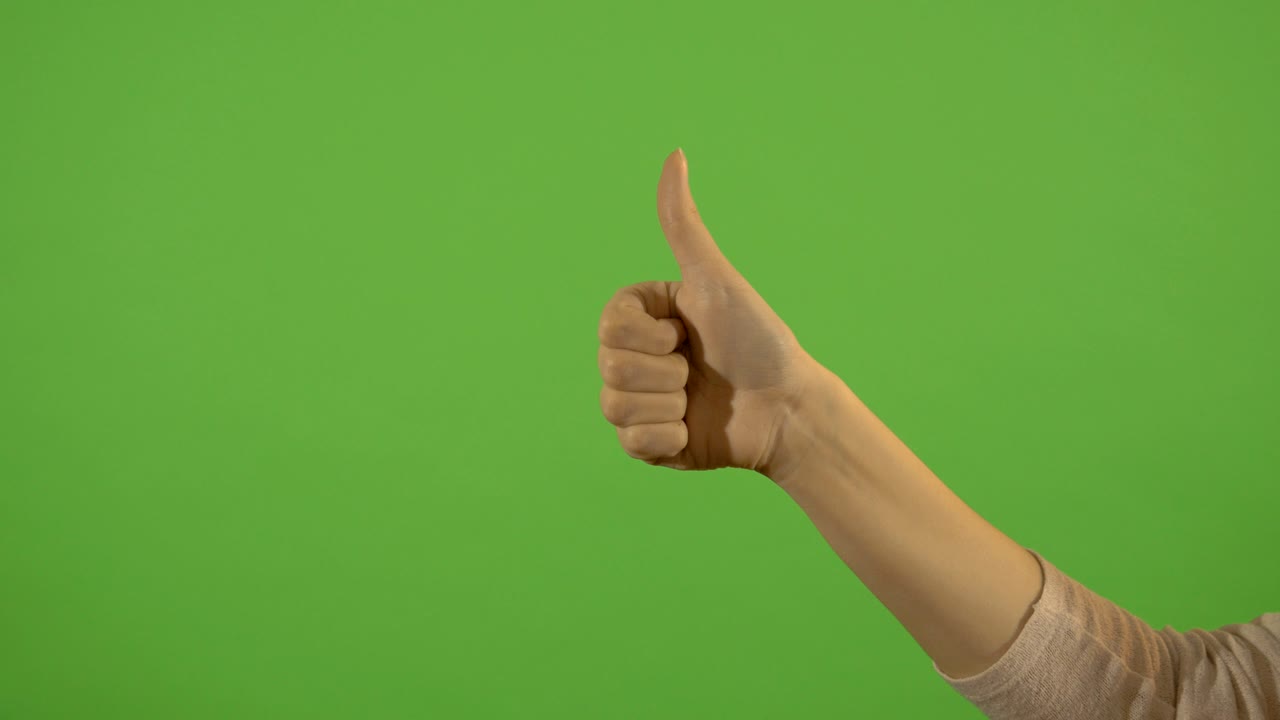 mano femenina, gesto de pulgar hacia arriba, sobre un fondo verde. todo está bien y hermoso