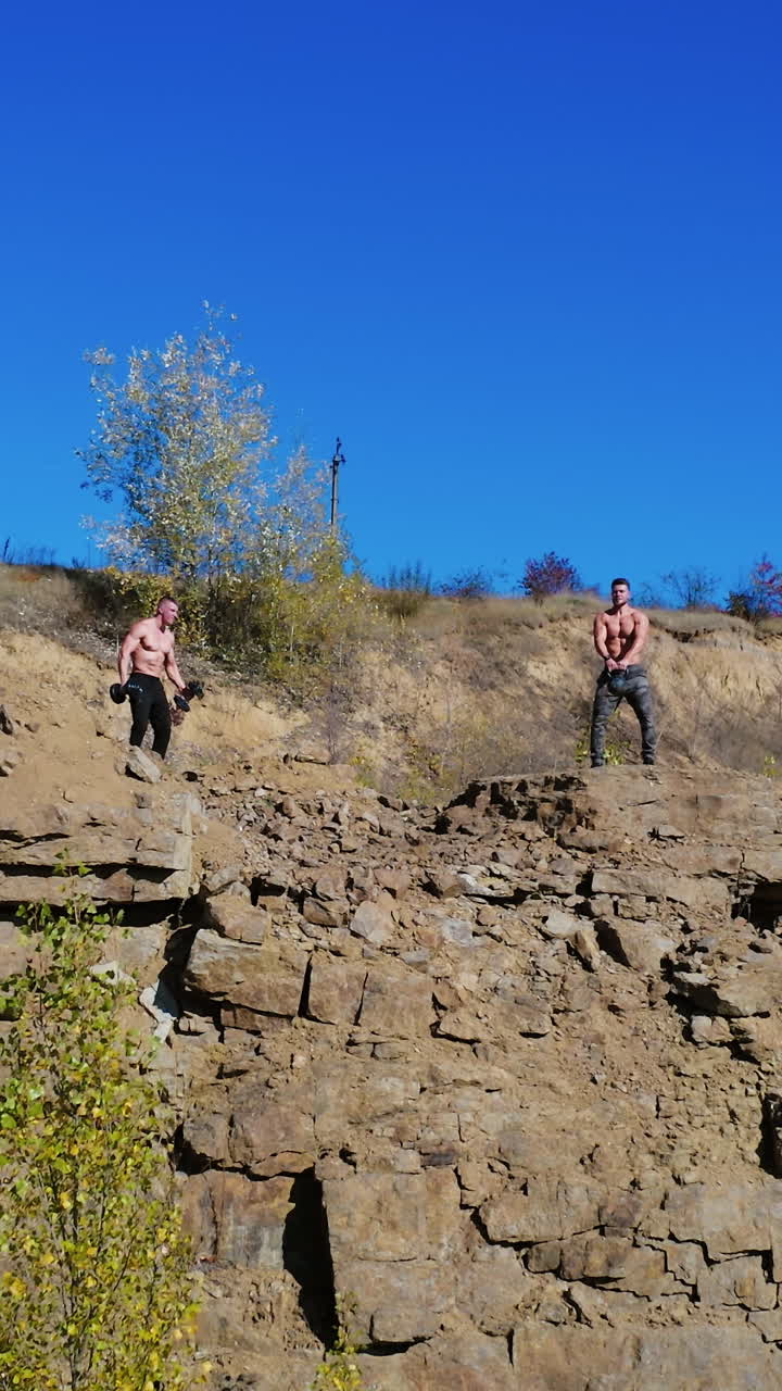 Athletes exercising with dumbbells. Male young athlete in nature with dumbbells