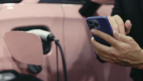 person charging an electric car with a smartphone
