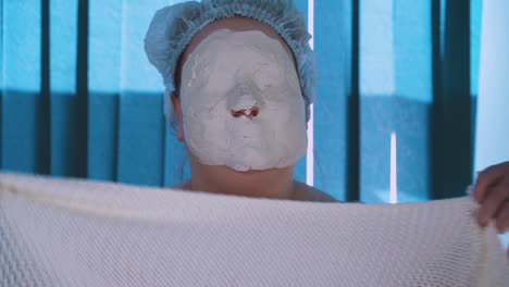 plus-size woman with dry alginate mask touches face closeup