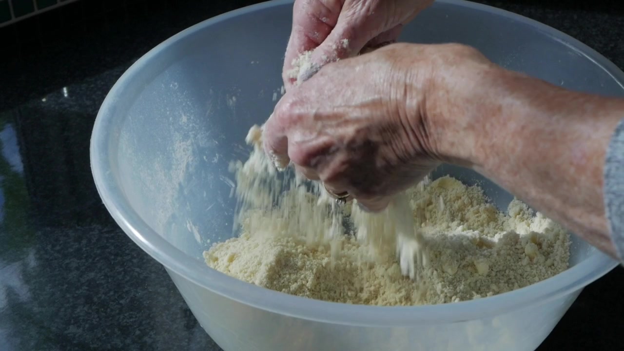 Donna che mescola burro e farina in una grande ciotola per preparare un impasto - Rallentatore 60fps