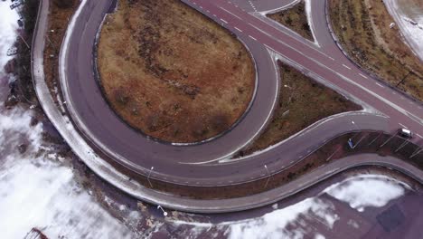 Drone-ascending-above-road-in-Vansbro,-Sweden,-a-cloudy-winter-day