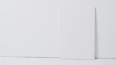 Vertical-video-of-white-canvas-sign-with-copy-space-on-floor-against-white-background