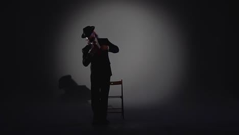 a man in a suit and fedora in a dramatic spotlight