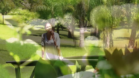 video compuesto de un primer plano de hojas contra una mujer caucásica caminando en el jardín