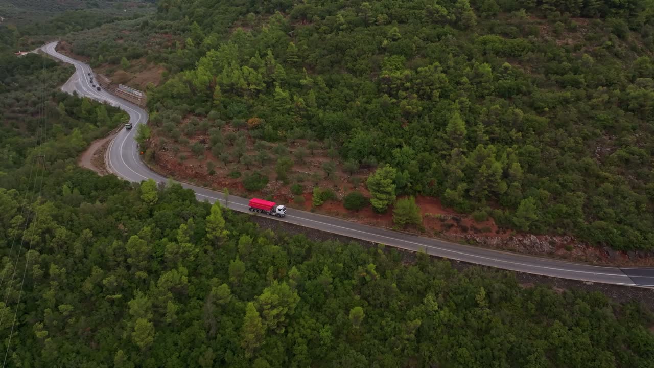 Vista aerea di un camion che percorre una strada tortuosa tra scogliere e vegetazione