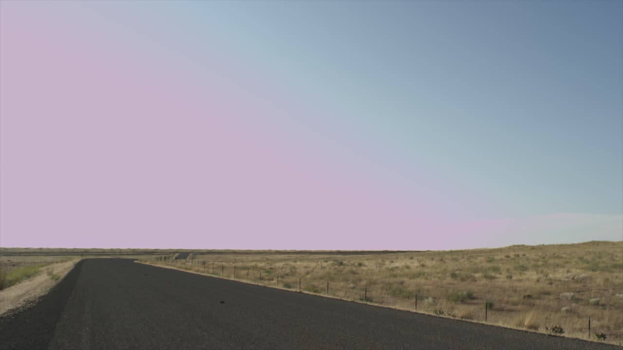 dry desert rocky grassland landscape. low shot down a desolate road