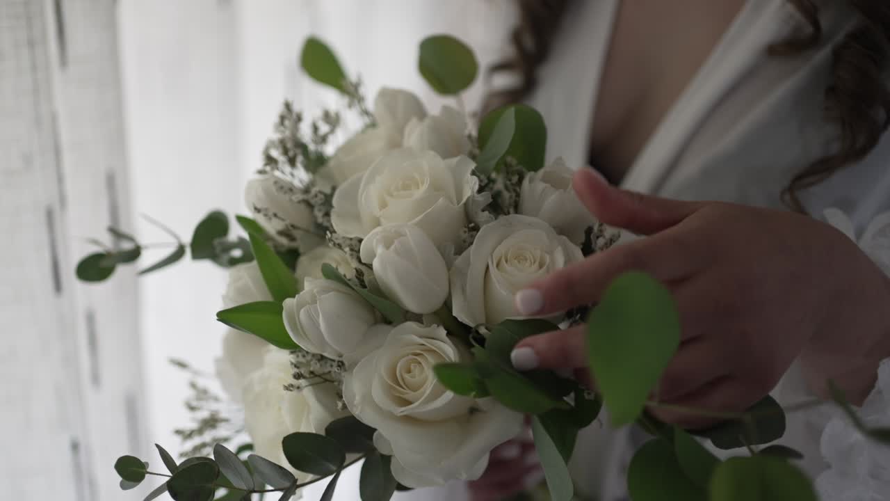 Bouquet da sposa di rose bianche tenuto delicatamente prima della cerimonia nuziale