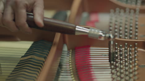 un hombre afina un piano con herramientas especiales