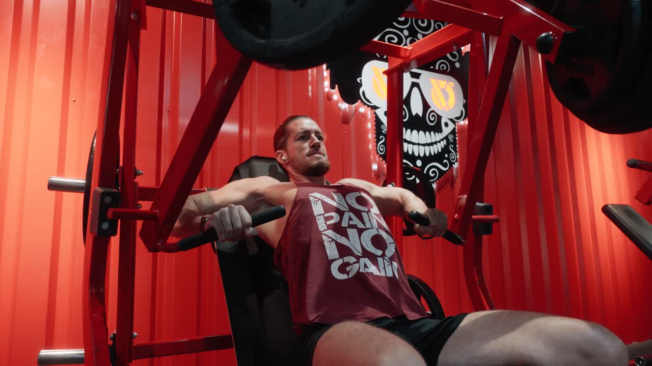 vista lateral de un hombre terminando su serie de press de pecho inclinado con peso